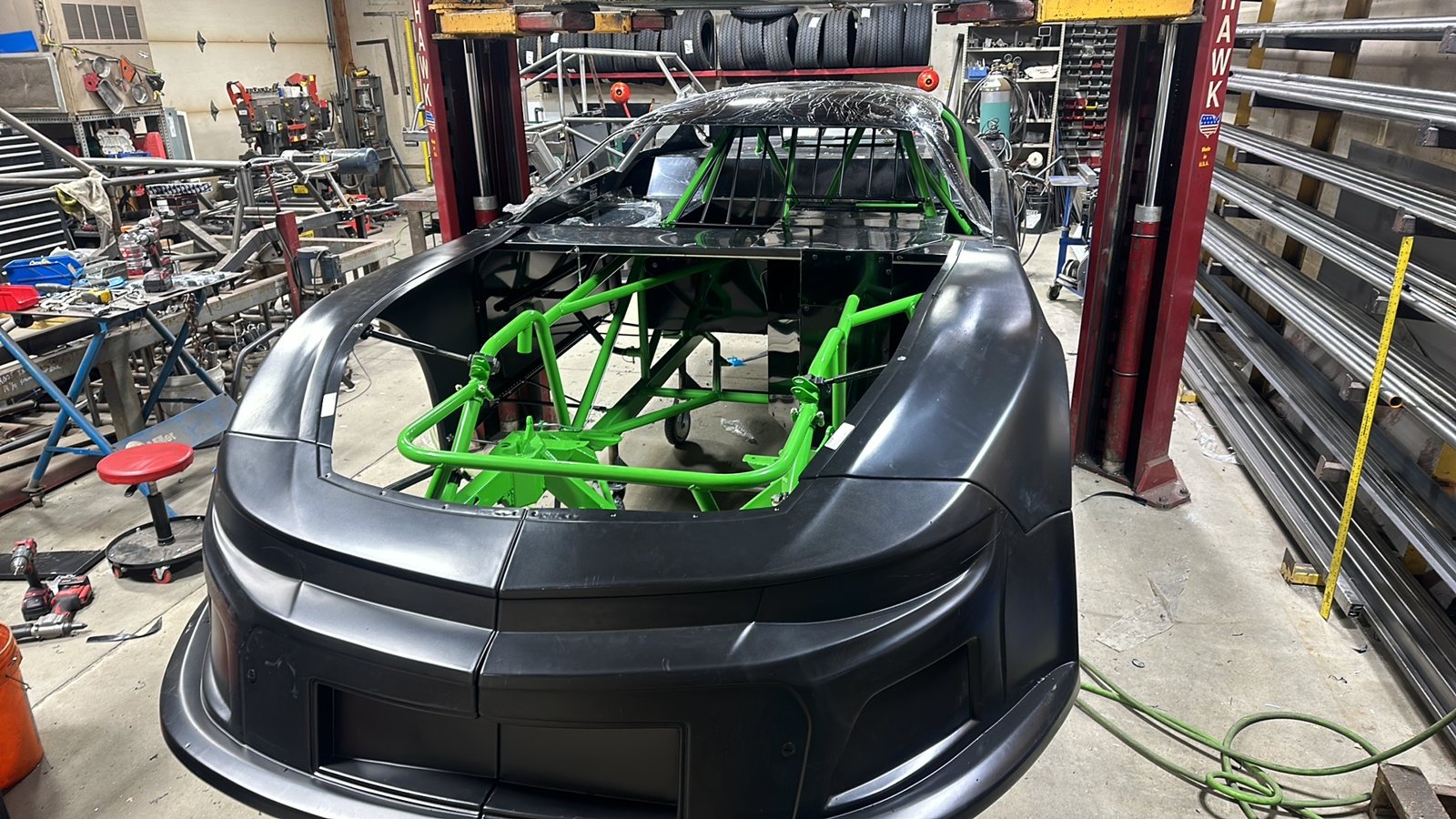 A green Manimal chassis with its body going on, in Nick's shop